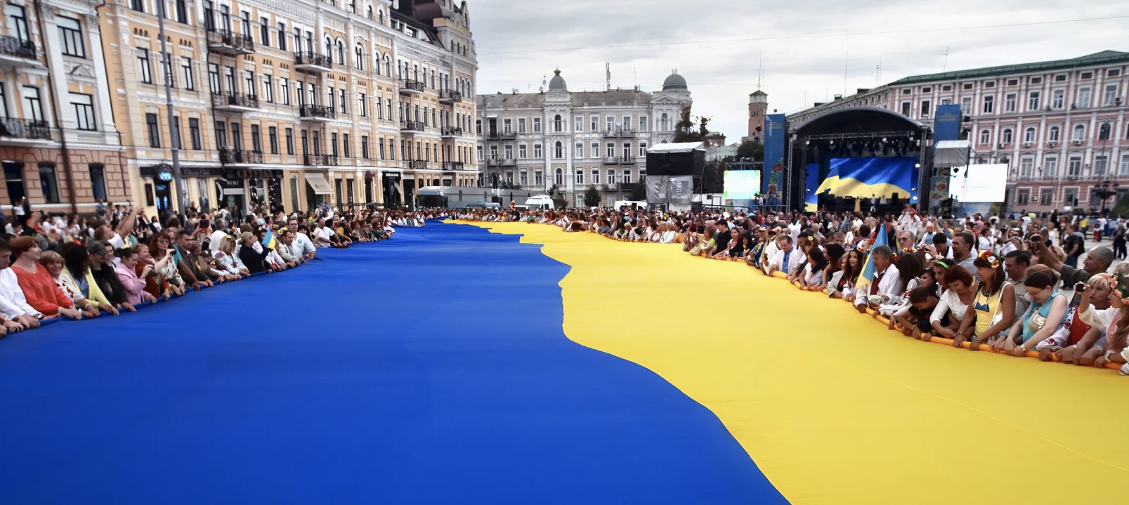 People holding a giant Ukrainian flag during a unity event in Kyiv, symbolising resilience and hope.